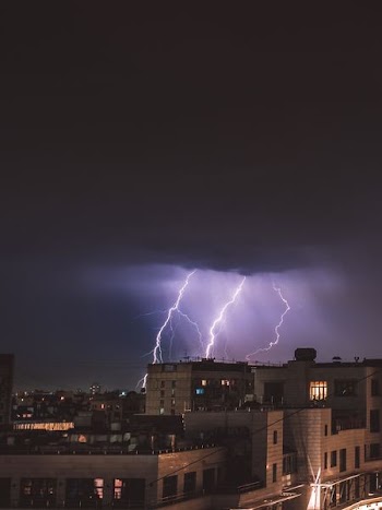 lightning over concrete buildings during nighttime