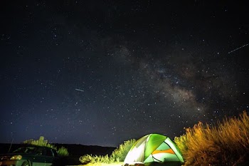 lit green dome tent under moonless skies