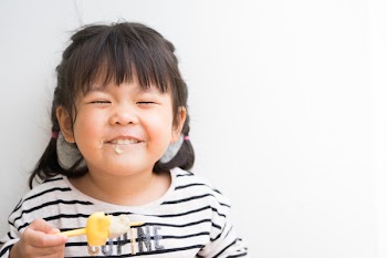 Little asian girl feeling happy while eating homemade avocado ice cream bar