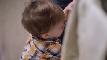 Little boy at his parent's feet in the kitchen, and hanging off of ...