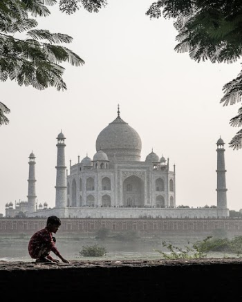 Little Boy Crouching on a Wall with Taj Mahal in the Background