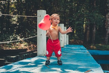 Little Boy Wearing Red Shorts Holding Red Balloon