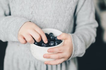 Little girl holding a bowl of blueberries