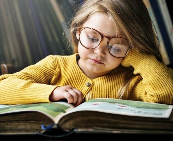 Little girl wearing eyeglasses reading | Free Photo - rawpixel