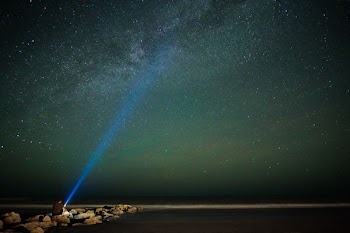 long exposure photography of person holding turned on flashlight during nighttime