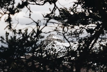 Long Shot Photo Of Snow Covered Mountain Peak Under Gray Cloudy Skies