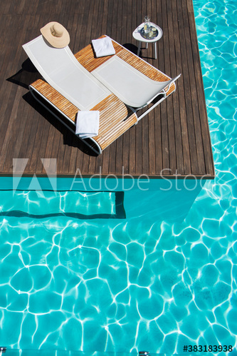 Lounge chairs at idyllic sunny summer poolside