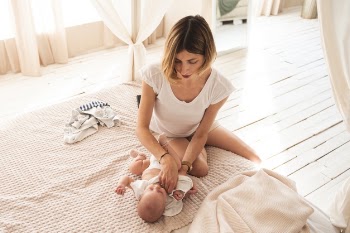 Lovely mom dressing newborn baby Free Photo