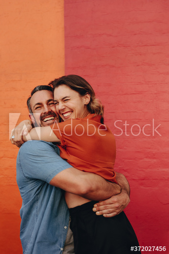 Loving couple embracing against colored wall