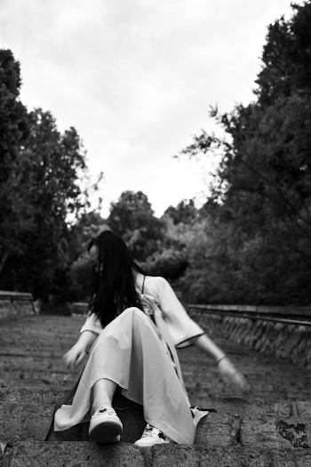 Low Angle Grayscale Photo of Woman Sitting on Concrete Staircase