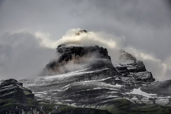 low angle photo of gray and black rugged mountain and clouds at daytime
