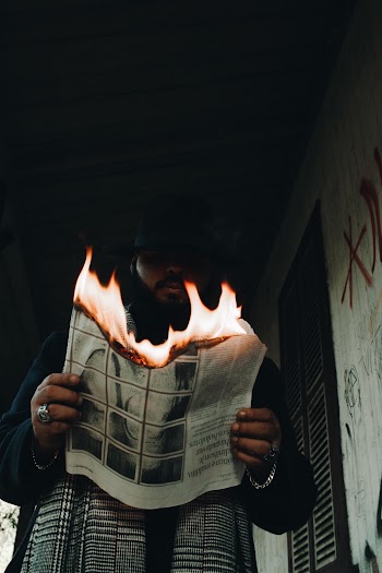 Low-Angle Photo of Man Holding a Burning Newspaper