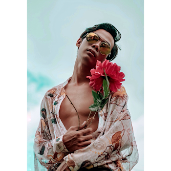 Low Angle Photo of Man in Floral Shirt and Sunglasses Posing while Holding a Red Flower