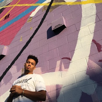 Low Angle Photo of Man in White Shirt Standing by Graffiti Wall