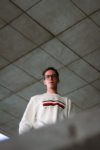Low Angle Photo of Man in White Tommy Hilfiger Sweatshirt and Glasses Looking Down