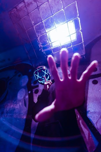 Low Angle Photo of Person Wearing LED Mask While Doing Silence Gesture