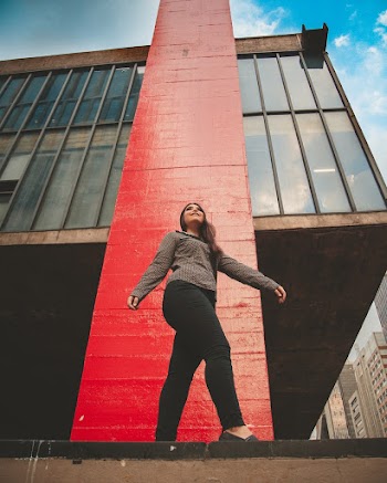 Low Angle Photo of Smiling Woman Posing Next to Building
