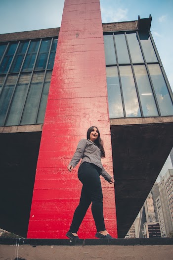 Low Angle Photo of Smiling Woman Standing on Her Toes Next to Building