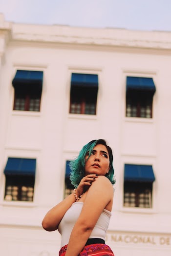 Low Angle Photo of Standing Woman Posing In Front of White Building