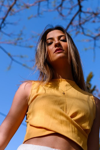 Low Angle Photo of Woman in Yellow Crop Top Posing While Looking Down