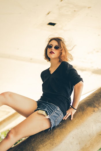 Low Angle Photo of Woman Leaning on Pillar