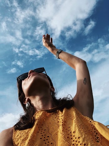 Low-angle Photo of Woman Raising Left Hand on Air Under Cloudy Sky
