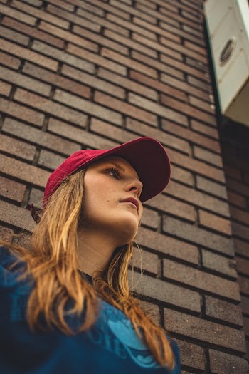 Low-Angle Photo of Woman Standing in Front of Brick Wall