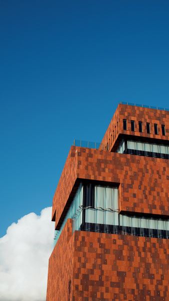 low angle photography of brown and gray building under blue and white sky