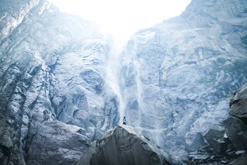 Low Angle Photography of Person Standing on Boulder Near Mountain
