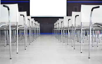 Low Angle Photography of Pile of Stainless Steel Chairs With Hanging Projector Canvas