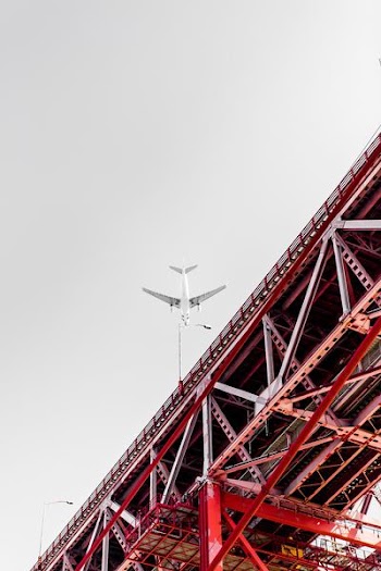 low angle photography of transportation plane above the bridge