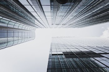 low-angle photography of two high rise curtain wall buildings under white clouds at daytime