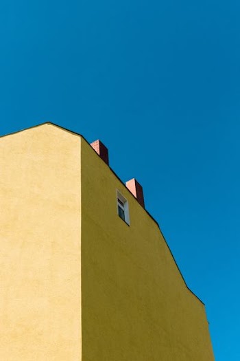 low-angle photography of yellow concrete building under blue sky
