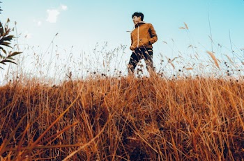 Low Angle Shot of a Man in Brown Jacket Standing in Grass Field