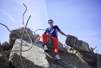 Low Angle Shot Of A Young Man In Colorful Active Wear Sitting On Top Of A Pile Of Rubble