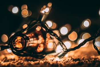 Low-light Photo of Amber Glass Bottle With String Lights and Beige Bokeh