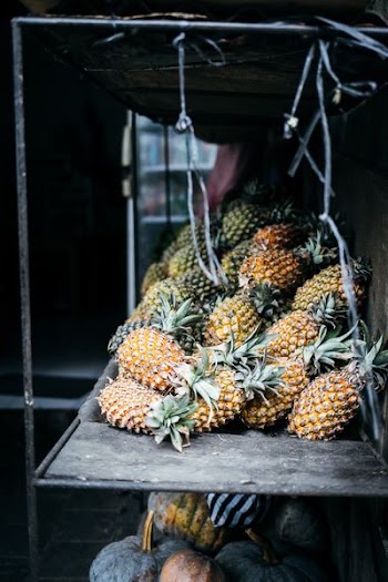low light photography of pineapples on wooden rack