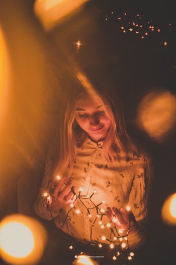 Low Light Photography of Woman in White Top Holding String Light