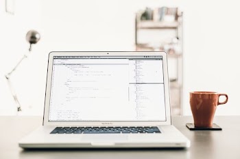 MacBOok Pro beside brown mug