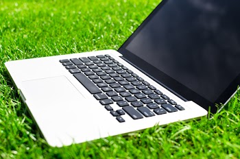 Macbook Pro With Turned Off Screen on Grass Field