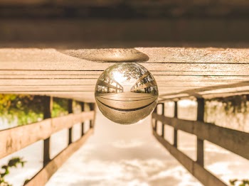 Macro Photography of Round Glass Ball on Top of Brown Wooden Dock