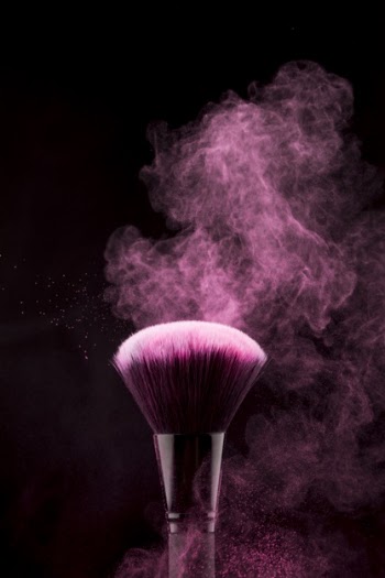 Makeup brush with flickering pink powder splash Free Photo