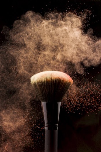 Makeup brush with peach color powder splash Free Photo