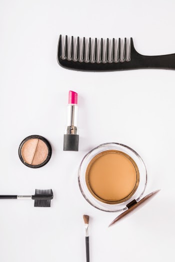 Makeup tools and cosmetics on white backdrop