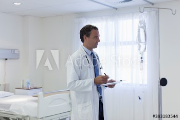 Male doctor checking IV drip in hospital room