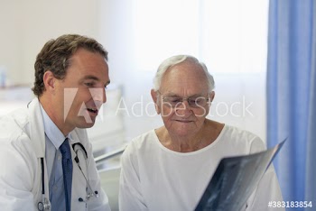 Male doctor showing x-ray to senior patient in hospital room