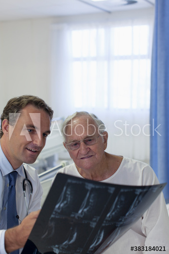 Male doctor showing x-rays to senior patient in hospital room