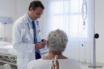 Male doctor talking with senior patient in hospital room