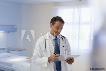 Male doctor with clipboard making rounds in hospital