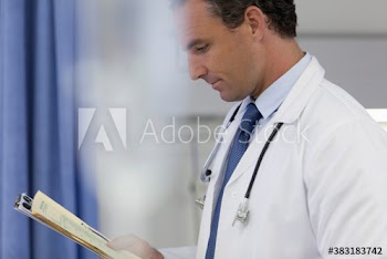 Male doctor with medical record making rounds in hospital